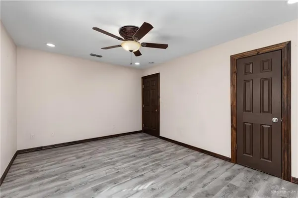an empty room with wooden floor closet and ceiling fan