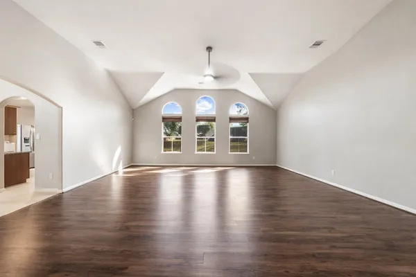 an empty room with wooden floor and windows