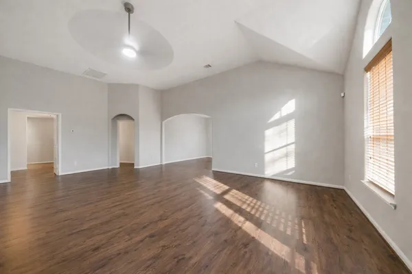a view of an empty room with wooden floor and a window