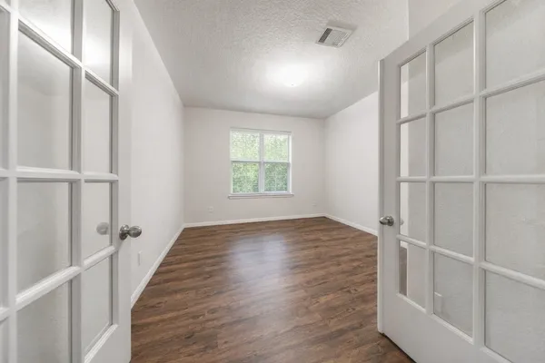 a view of an empty room with wooden floor and a window