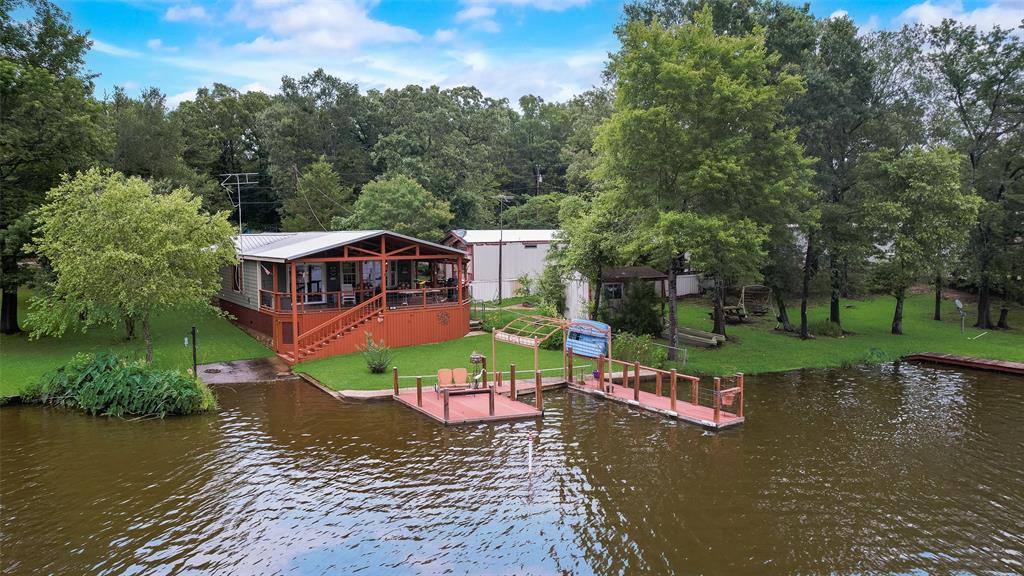 Dock with a water view, stairs, boat lift, and a yard
