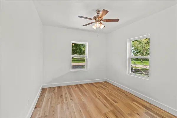 a view of empty room with wooden floor and fan