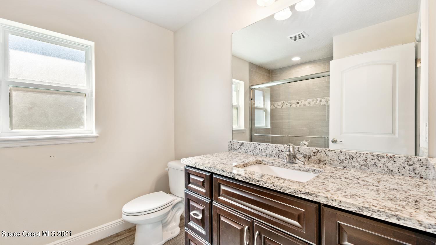 942 Carver Road Southeast Palm Bay, FL 32909 - Photo 14 of 26 a bathroom with a granite countertop sink a toilet and a mirror