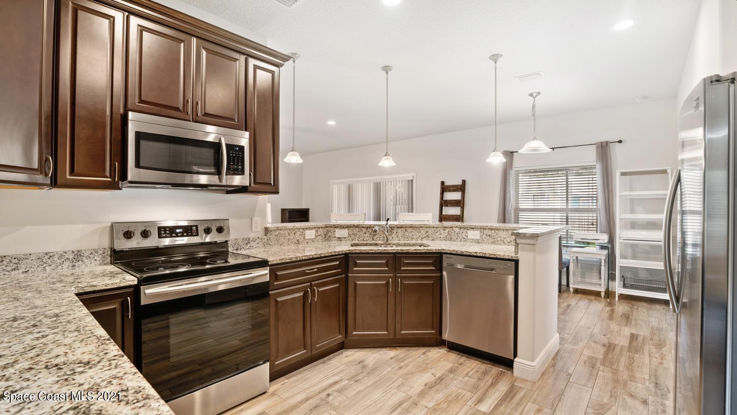 942 Carver Road Southeast Palm Bay, FL 32909 - Photo 22 of 26 a kitchen with stainless steel appliances granite countertop a stove a sink and a wooden floors