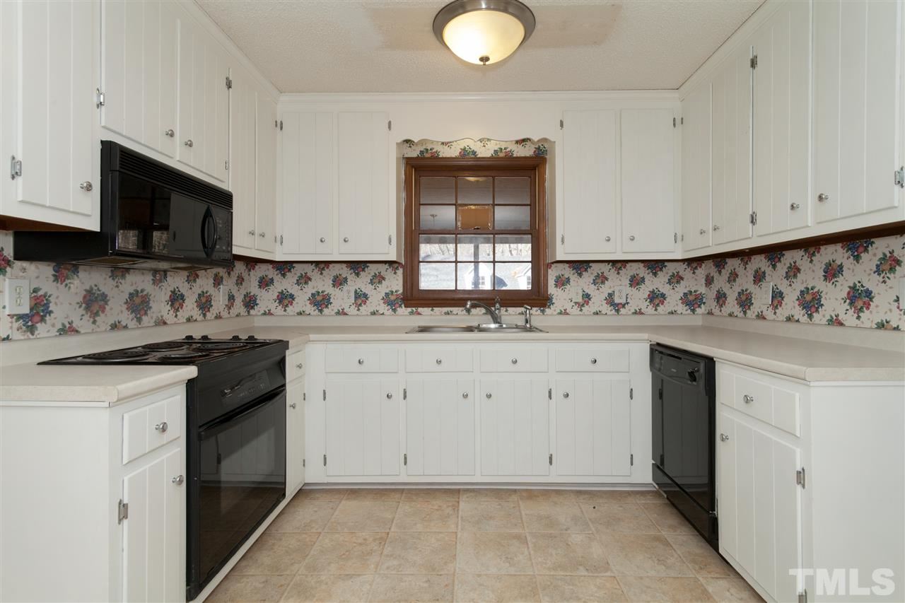 5827 Russell Road Durham, NC 27712 - Photo 8 of 25 a kitchen with granite countertop white cabinets and white appliances