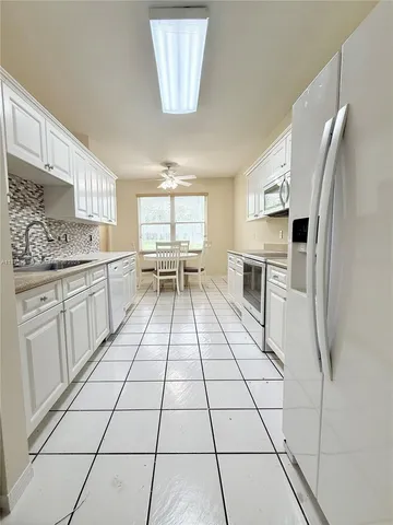 a kitchen with a sink a stove and white cabinets