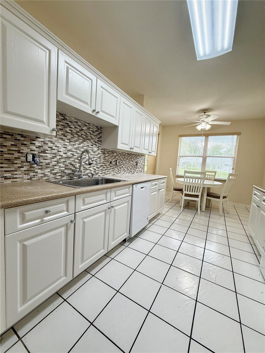8658 Vía Reale, Unit 3 Boca Raton, FL 33496 - Photo 8 of 39 a kitchen with a sink a stove and white cabinets