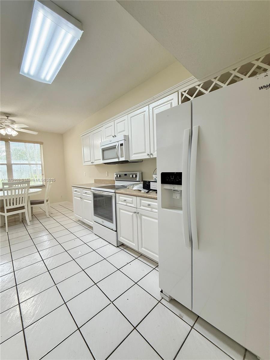 8658 Vía Reale, Unit 3 Boca Raton, FL 33496 - Photo 9 of 39 a kitchen with white cabinets and white appliances