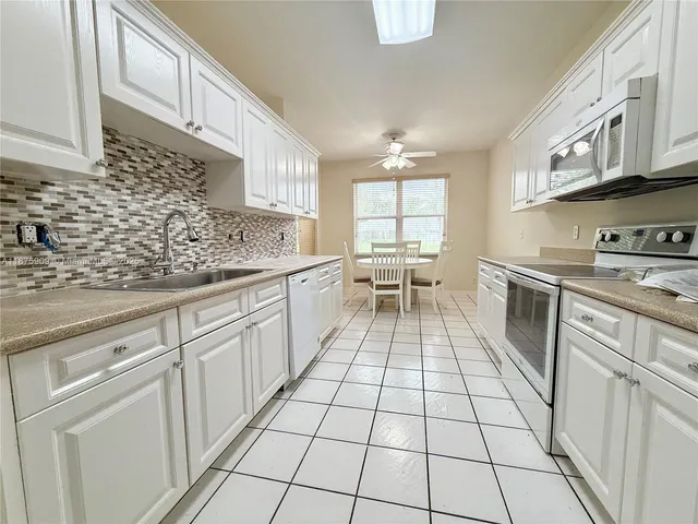 a kitchen with white cabinets a sink dishwasher and a stove with wooden floor