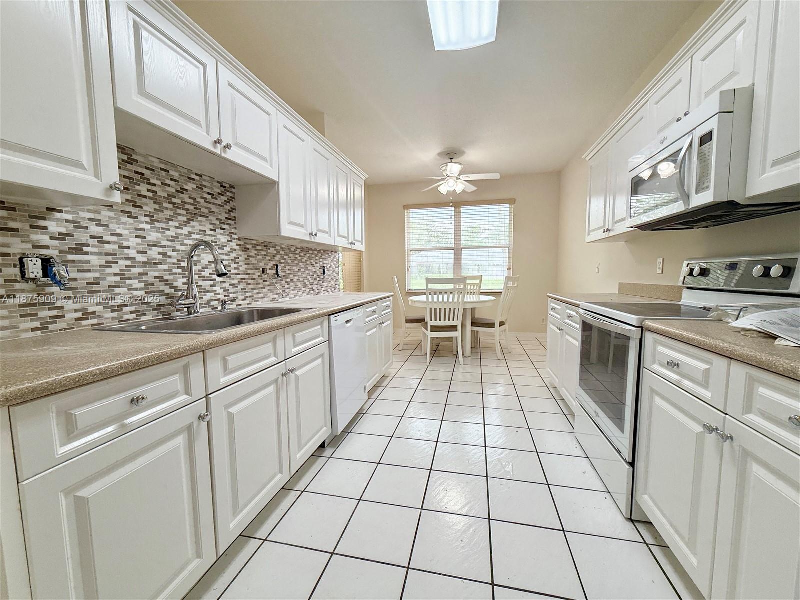 8658 Vía Reale, Unit 3 Boca Raton, FL 33496 - Photo 10 of 39 a kitchen with a sink a stove and cabinets