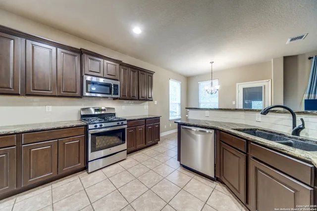 a kitchen with stainless steel appliances granite countertop a stove top oven a sink dishwasher a dining table and chairs