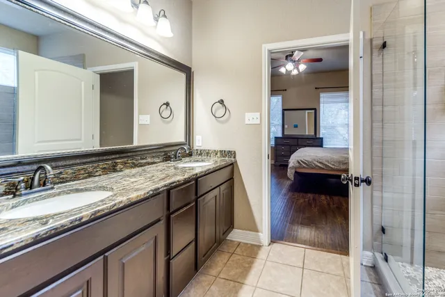 a en suite bathroom with a granite countertop sink and a mirror