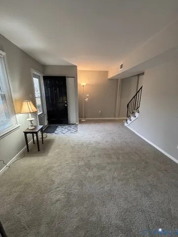 a view of an empty room with stairs and a window