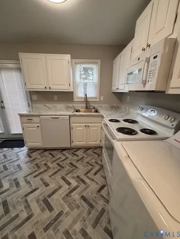 a kitchen with granite countertop white cabinets sink and stainless steel appliances
