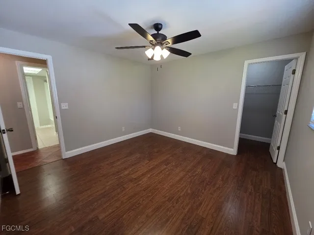 a view of an empty room with wooden floor and fan