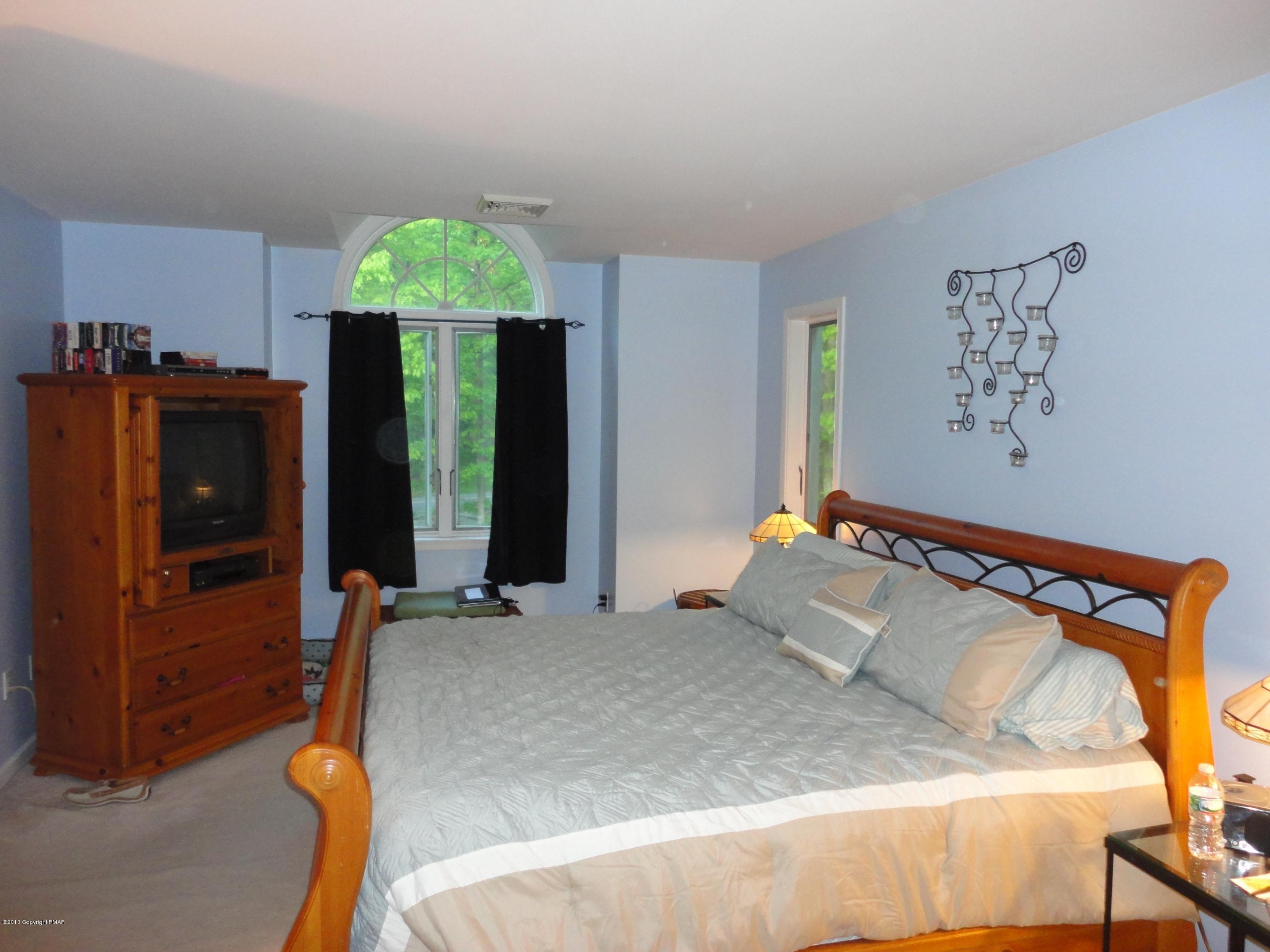 391 Turkey Ridge Road Mount Bethel, PA 18343 - Photo 9 of 19 a bedroom with a bed and a chandelier