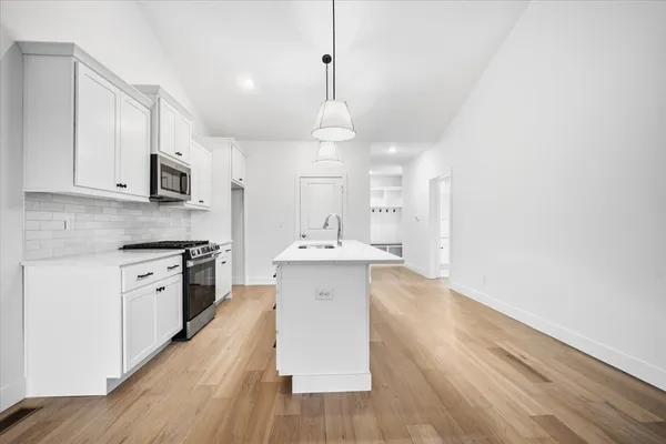 a large kitchen with a sink stainless steel appliances and wooden floor