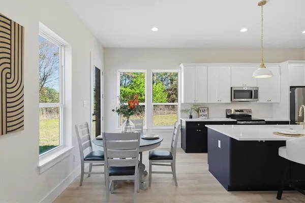 a kitchen with granite countertop a stove a sink a dining table and chairs