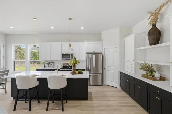 a kitchen with a refrigerator a sink dishwasher a dining table and chairs with wooden floor