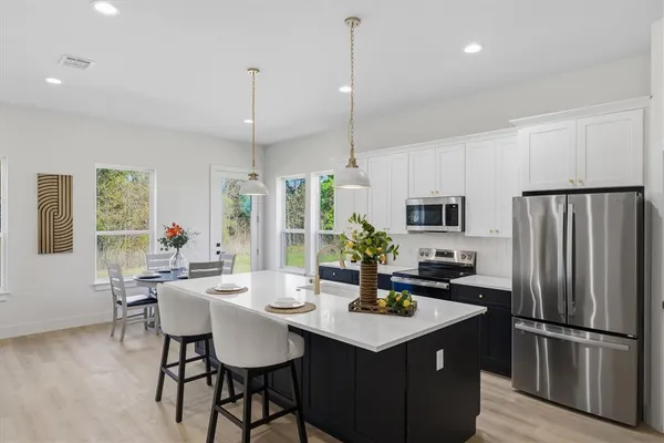 a kitchen with sink refrigerator dining table and chairs