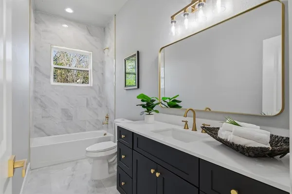 a bathroom with a granite countertop sink a toilet and tub