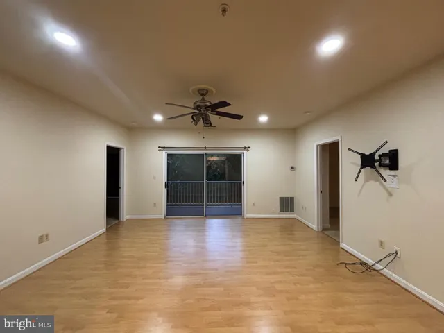 an empty room with wooden floor and a ceiling fan