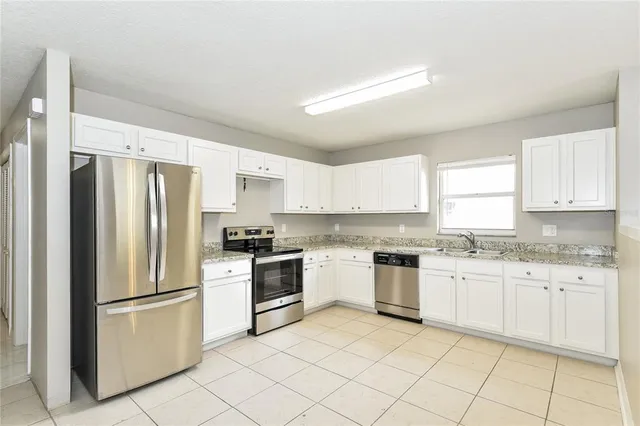 a kitchen with granite countertop stainless steel appliances a refrigerator sink and cabinets