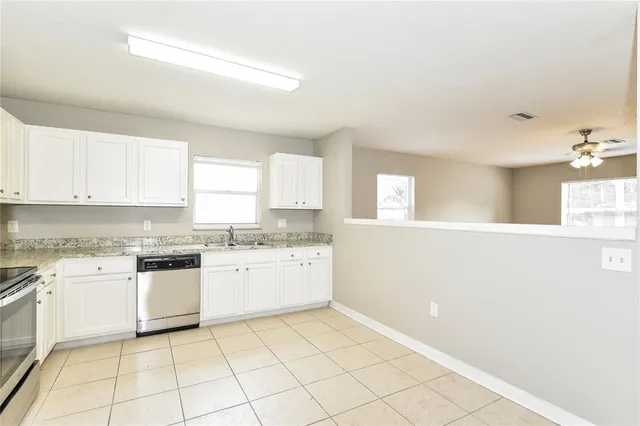a kitchen with a sink a stove top oven and white cabinets
