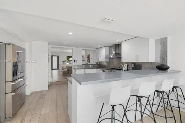 a kitchen with stainless steel appliances kitchen island granite countertop a refrigerator and a sink