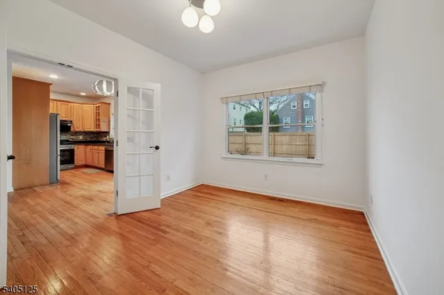 a view of an empty room with window and wooden floor