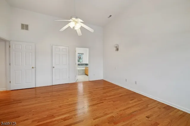 a view of empty room with wooden floor and ceiling fan