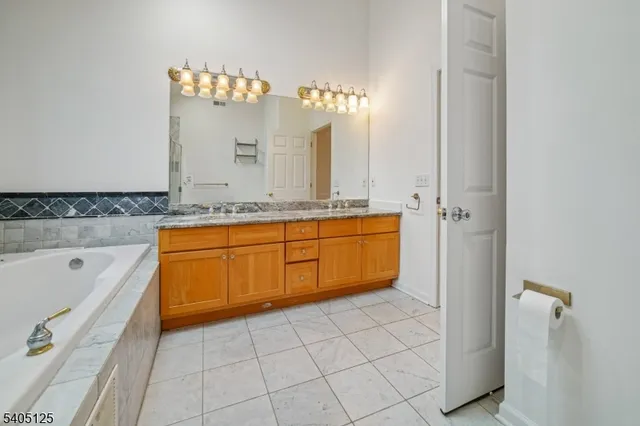 a bathroom with a tub a double vanity sink a mirror and a shower