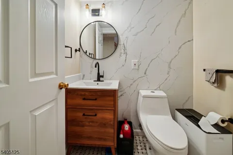 a bathroom with a toilet sink vanity granite and mirror