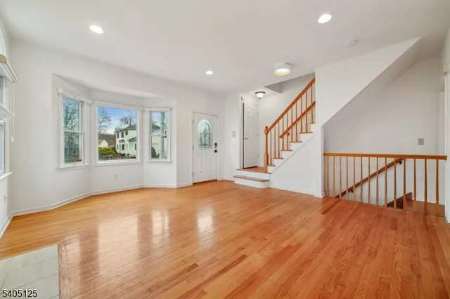 a view of an empty room with wooden floor and windows