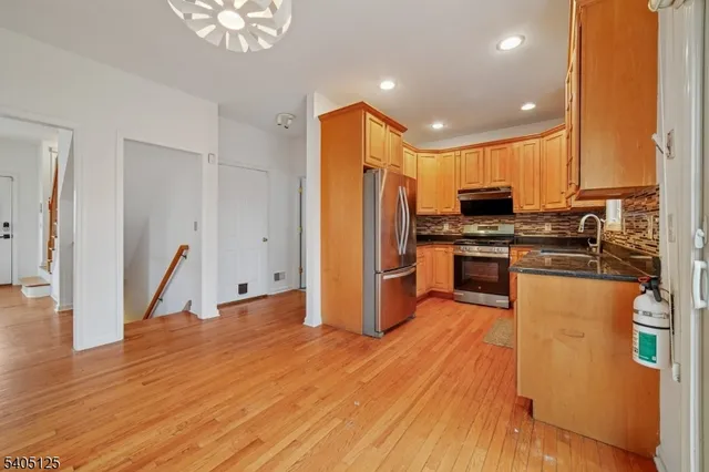 a kitchen with stainless steel appliances granite countertop a refrigerator a stove and a wooden floors