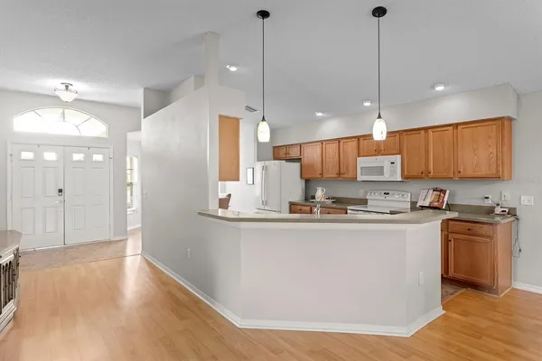 a kitchen with stainless steel appliances a refrigerator a sink dishwasher a stove and white cabinets with wooden floor