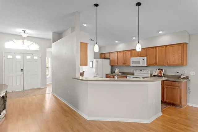 a kitchen with stainless steel appliances a refrigerator a sink dishwasher a stove and white cabinets with wooden floor