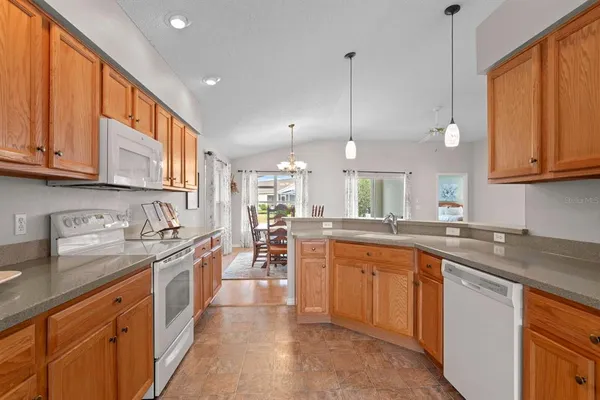 a kitchen with stainless steel appliances granite countertop a sink a stove and a wooden cabinets