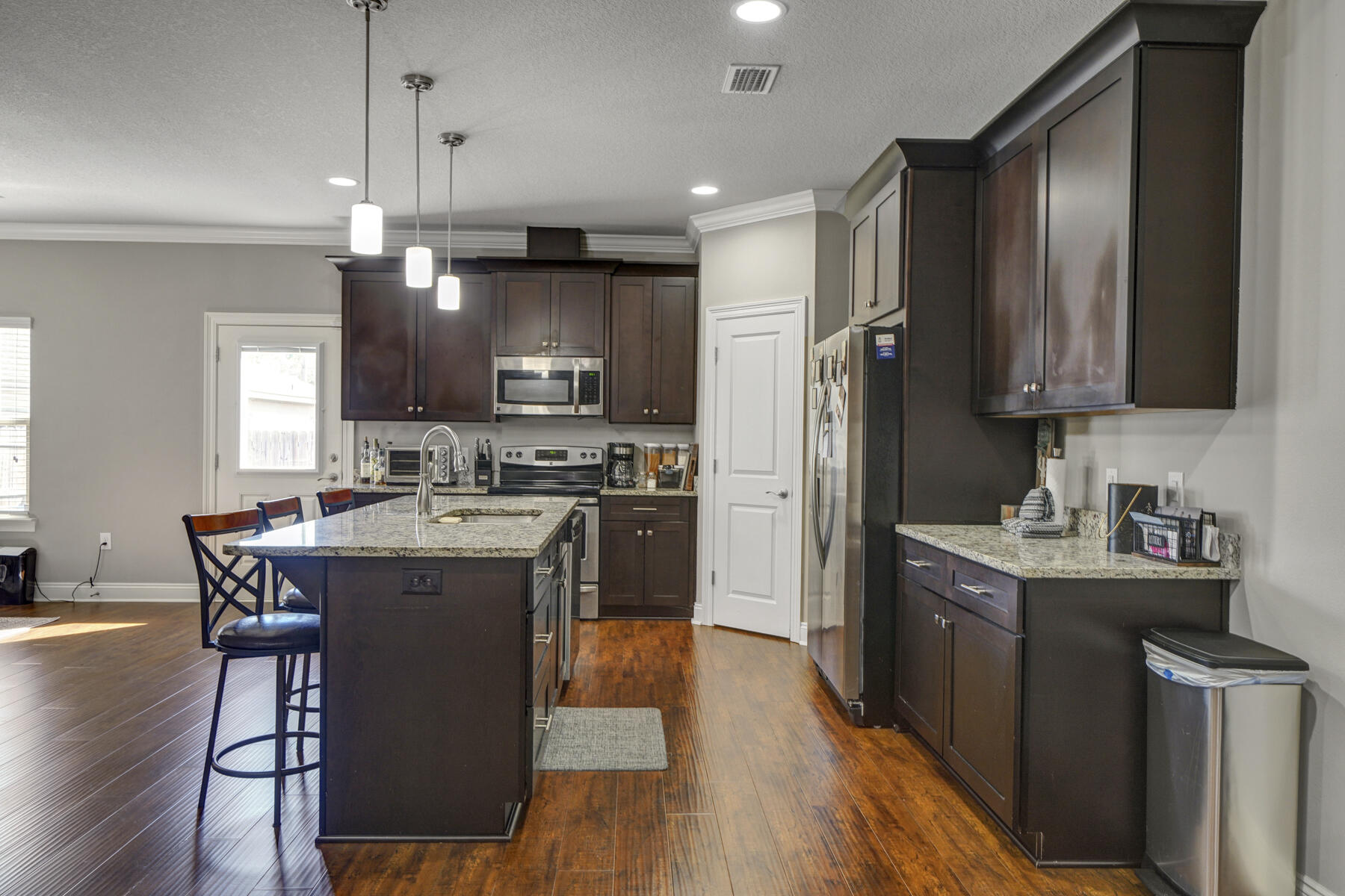 2136 Nina Street Navarre, FL 32566 - Photo 8 of 28 a kitchen with kitchen island granite countertop wooden floors stainless steel appliances and a center island