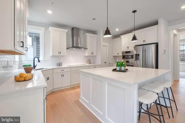 a kitchen with stainless steel appliances granite countertop a sink a stove a refrigerator a center island and cabinets