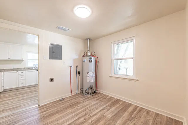 a view of an empty room with window and wooden floor
