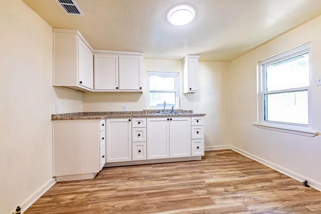 a view of a kitchen with wooden floor and cabinets