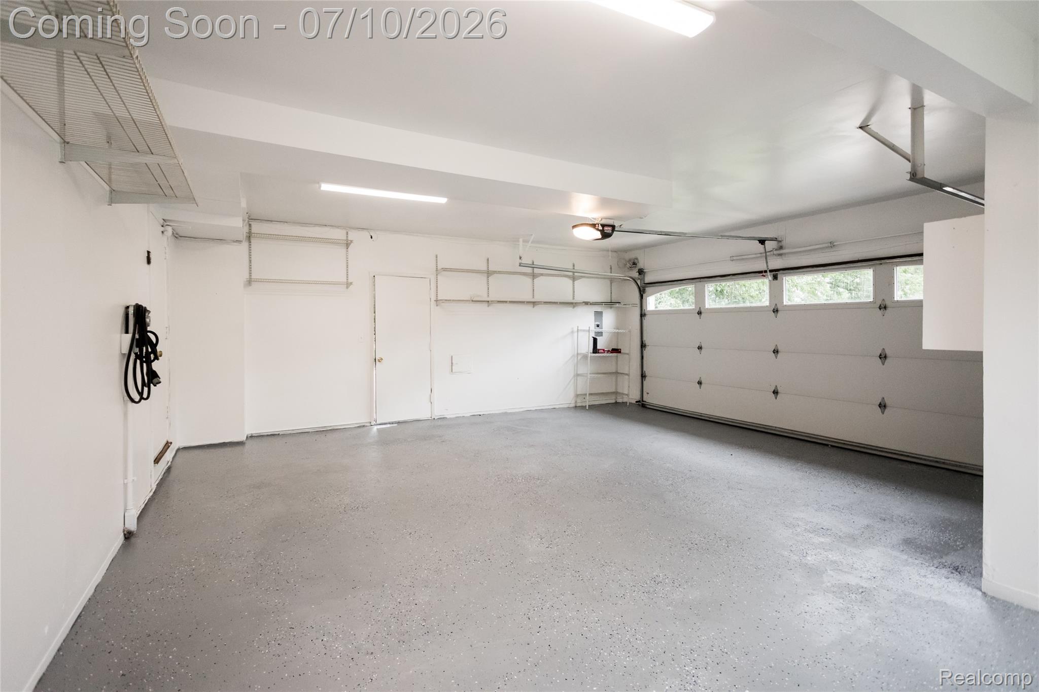 600 Middlesex Road Grosse Pointe, MI 48230 - Photo 37 of 43 Spacious garage featuring a durable epoxy floor, integrated overhead shelving, an electric vehicle charging station, multiple fluorescent light fixtures, and a garage door with upper window panels