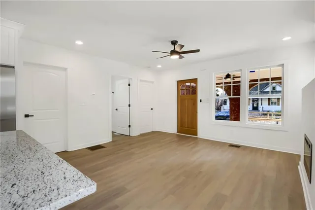 a view of empty room with wooden floor and ceiling fan