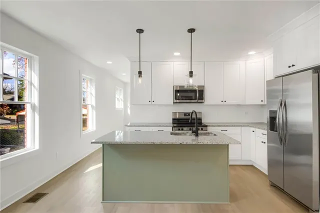 a kitchen with stainless steel appliances granite countertop a sink a refrigerator and a granite counter tops