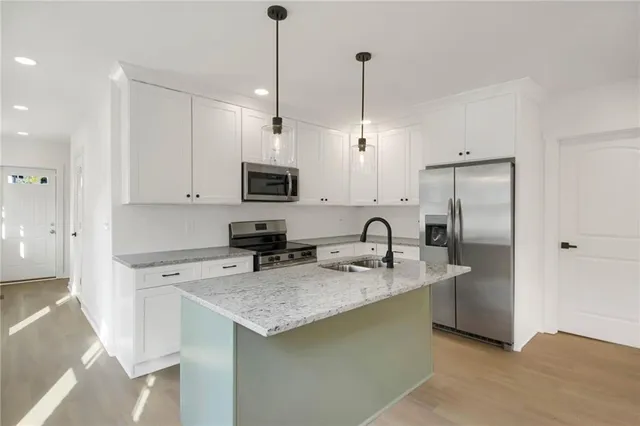 a kitchen with stainless steel appliances granite countertop a sink a refrigerator a stove a microwave and island