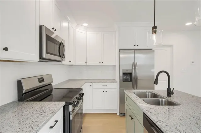 a kitchen with granite countertop a sink stainless steel appliances and cabinets