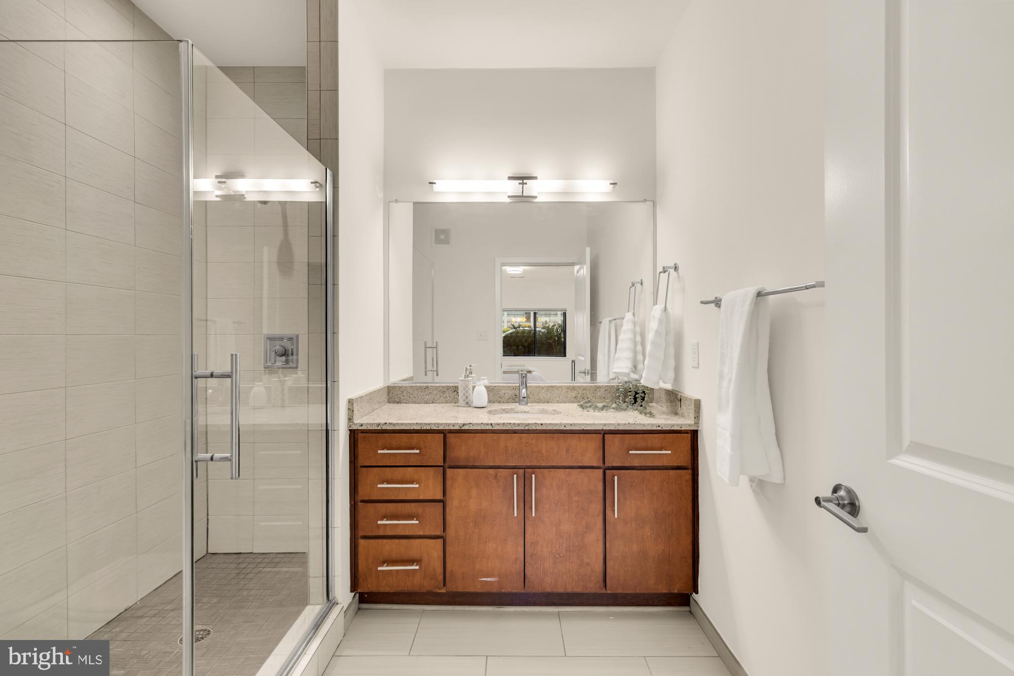 8005 13th Street, Unit 104 Silver Spring, MD 20910 - Photo 21 of 34 a bathroom with a granite countertop sink a mirror and a shower