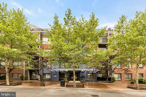 a front view of a building with street view and trees