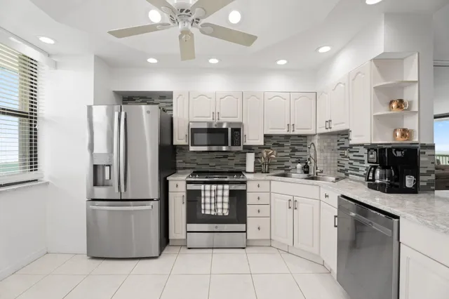 a kitchen with stainless steel appliances granite countertop a refrigerator a sink and white cabinets